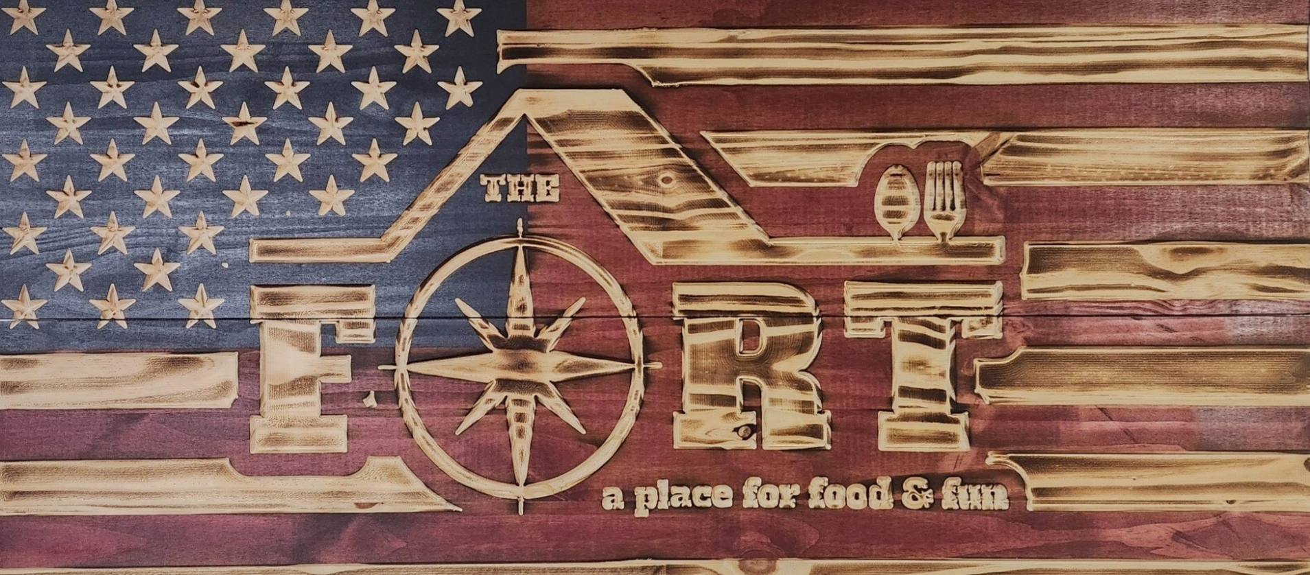 The Fort's hand-carved wooden flag sign reading 'The Fort, a place for food and fun'